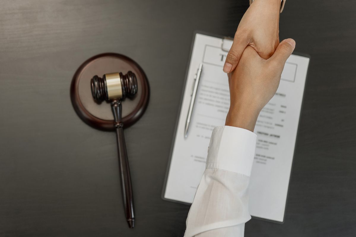 A lawyer shakes hands with a judge's gavel on a desk, symbolizing collaboration in corporate law for eCommerce businesses.