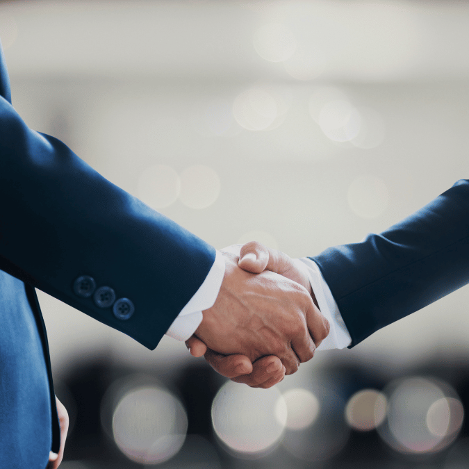 Two professionals shaking hands in an office, symbolizing the successful negotiation of a Broker Agreement.